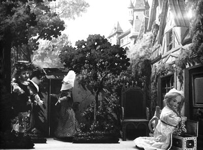 Marguerite se tient accroupie dans une arrière cours, un coffre ouvert, rempli de bijoux, devant elle.