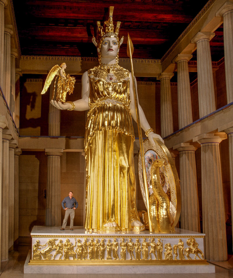 Alan LeQuire, Athena Parthenos, 1990, plâtre, bronze, dorure, 
H : 1280,16 cm, Parthenon of Nashville, Tennessee. ©Wikipédia.
L’artiste pose à côté de sa sculpture.
